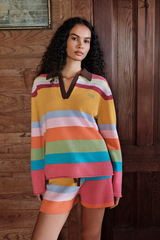 Woman wearing a colorful striped sweater and shorts against a wooden background |M1