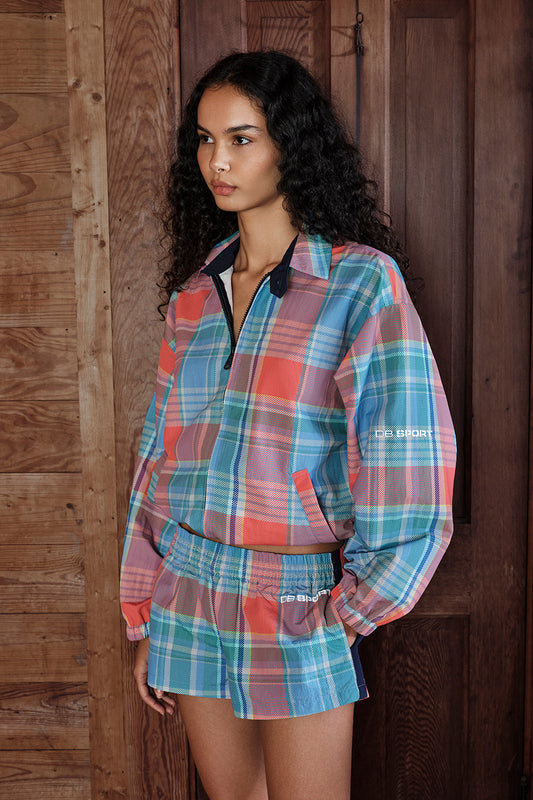 Woman wearing a plaid outfit with a visible brand logo against a wooden background |M1
