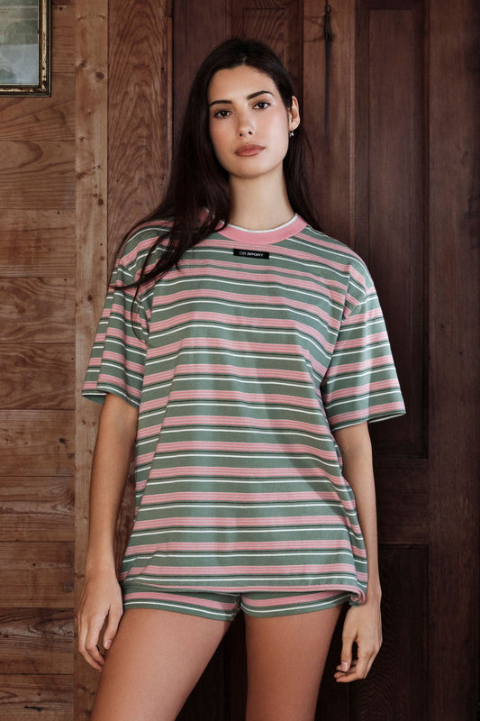 Woman wearing a striped shirt and shorts in front of a wooden wall |M1